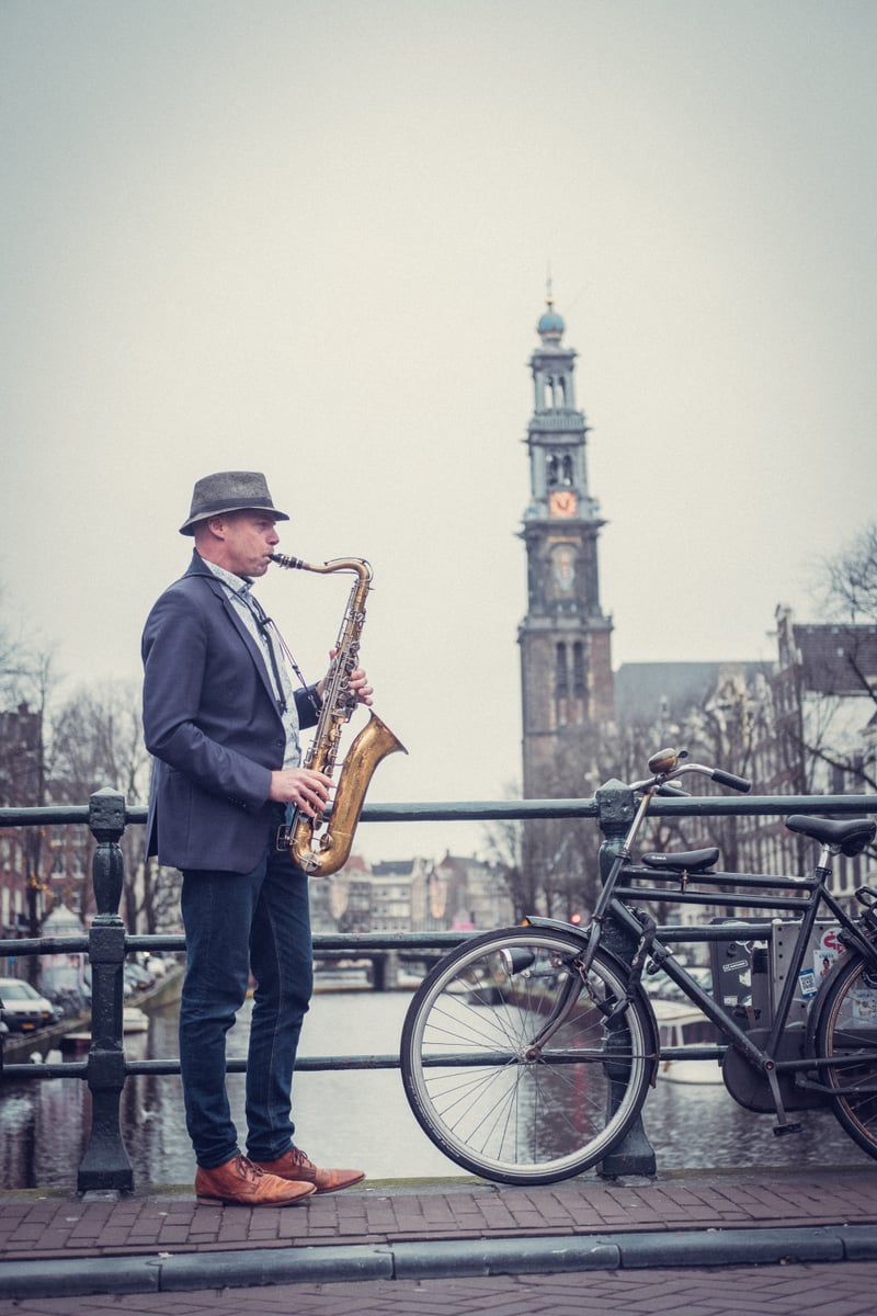 Tal playing saxophone on Amsterdam canal bridge with Westerkerk